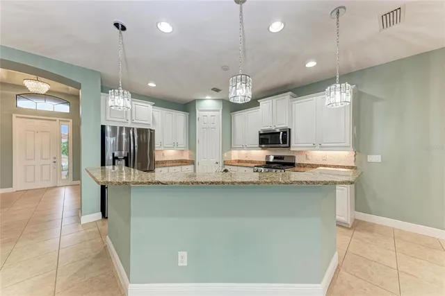 a view of a kitchen with kitchen island a sink stainless steel appliances and cabinets