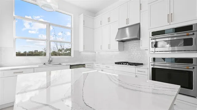 a kitchen with stainless steel appliances white cabinets and a stove top oven