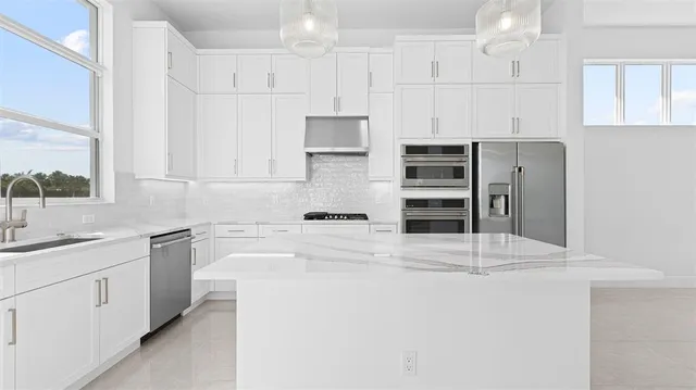 a kitchen with stainless steel appliances a refrigerator and white cabinets
