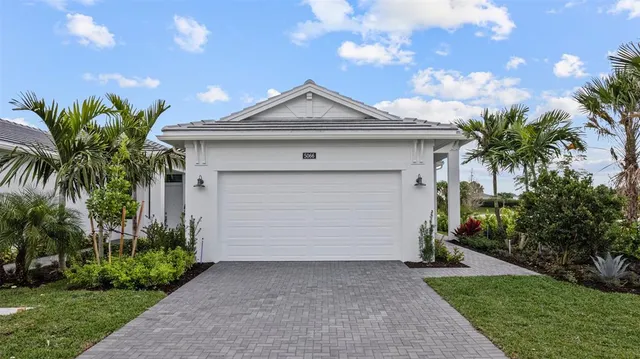 a view of a white house with a small yard and palm trees