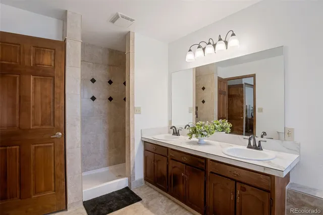 a bathroom with double vanity sinks and a shower
