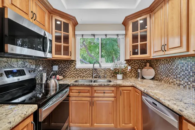 a kitchen with granite countertop a sink stove and cabinets