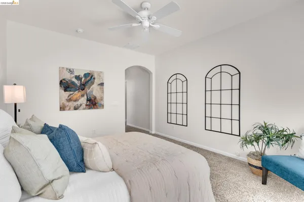 a spacious bedroom with a bed a couch and potted plant on the dresser