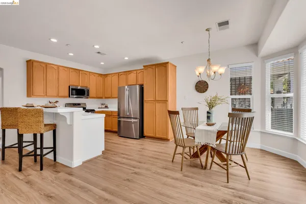 a view of kitchen with refrigerator a microwave oven a stove and a dining table with wooden floor