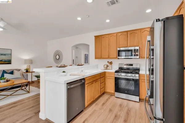 a kitchen with stainless steel appliances granite countertop a refrigerator a stove top oven a sink dishwasher and wooden cabinets with wooden floor