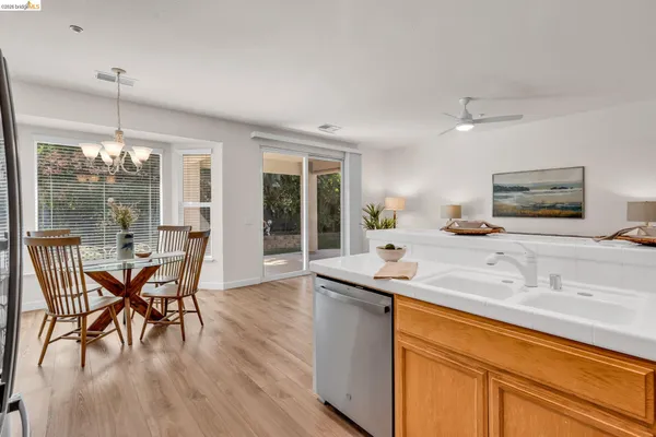 a dining hall with stainless steel appliances granite countertop a kitchen island a table and chairs in it