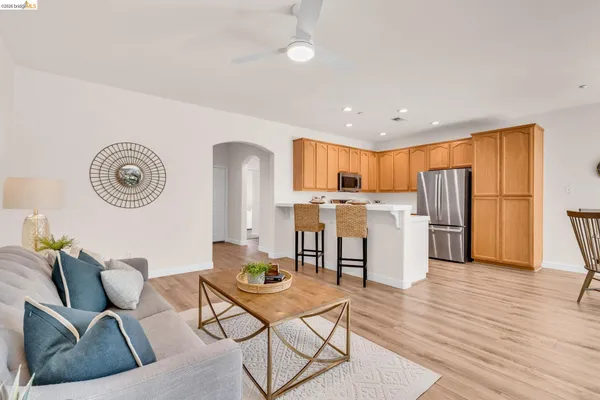 a living room with stainless steel appliances furniture a refrigerator and a kitchen view