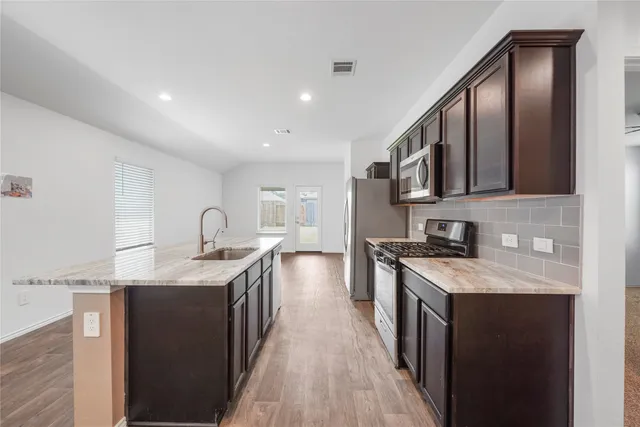 a kitchen with stainless steel appliances granite countertop a sink stove and cabinets