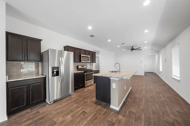a kitchen with stainless steel appliances granite countertop a refrigerator stove and sink