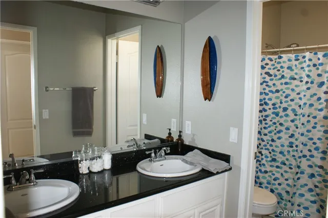 a bathroom with a double vanity sink toilet mirror and shower