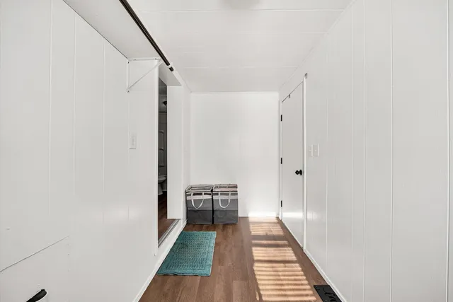 a view of a hallway with wooden floor and a bathroom