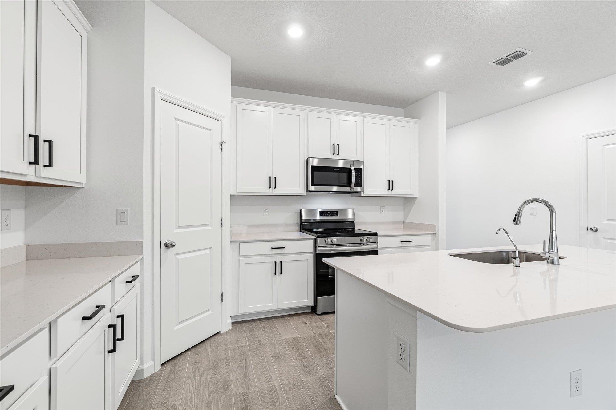 89 Kingsley Pk Way St. Augustine, FL 32084 - Photo 8 of 67 Kitchen with stainless steel appliances, white cabinets, light stone counters, light wood-style flooring, and recessed lighting