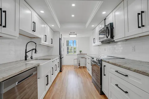 a kitchen with white cabinets stainless steel appliances a sink and a stove