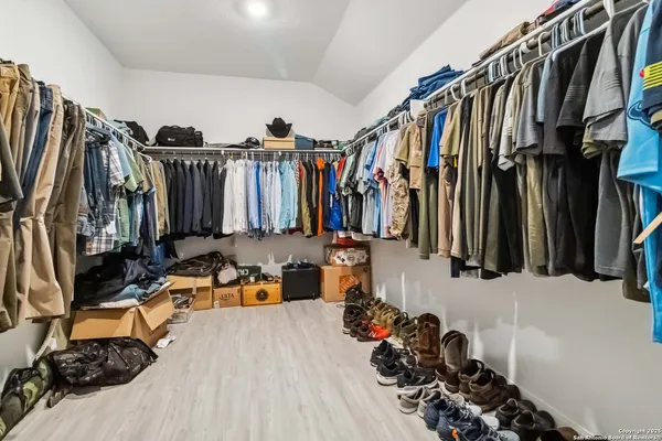 a view of walk in closet with clothes and shoes