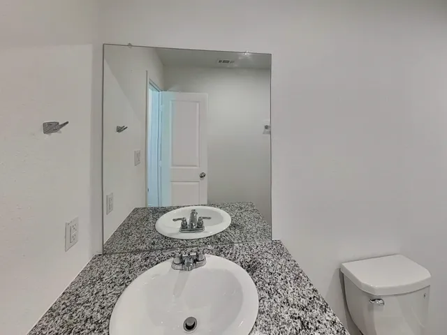 a bathroom with a sink a toilet and a mirror