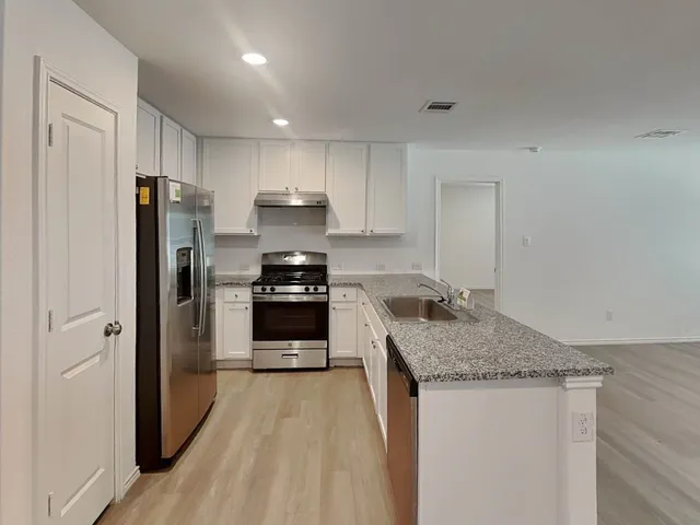 a kitchen with a refrigerator sink and cabinets