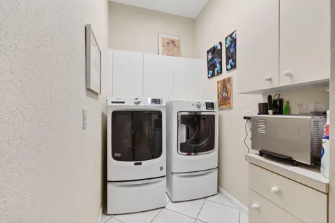 a utility room with stainless steel appliances a refrigerator and cabinets