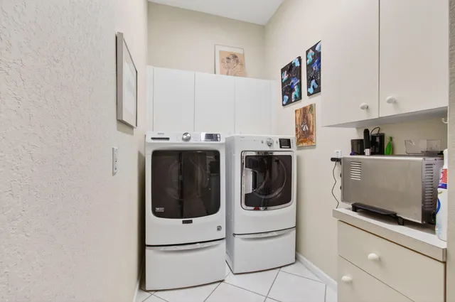 a utility room with stainless steel appliances a refrigerator and cabinets