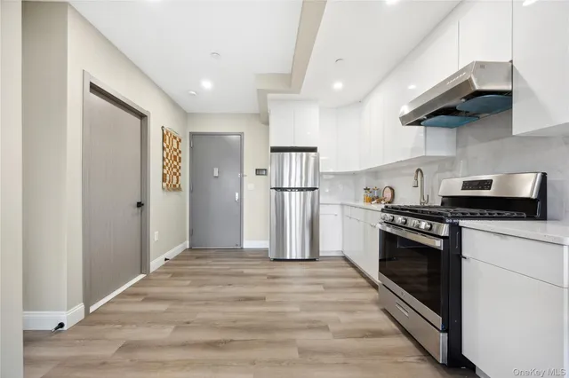 a kitchen with stainless steel appliances granite countertop a refrigerator a stove and a sink