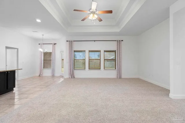 an empty room with chandelier fan and windows
