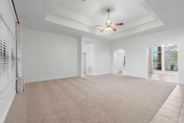an empty room with chandelier fan and windows