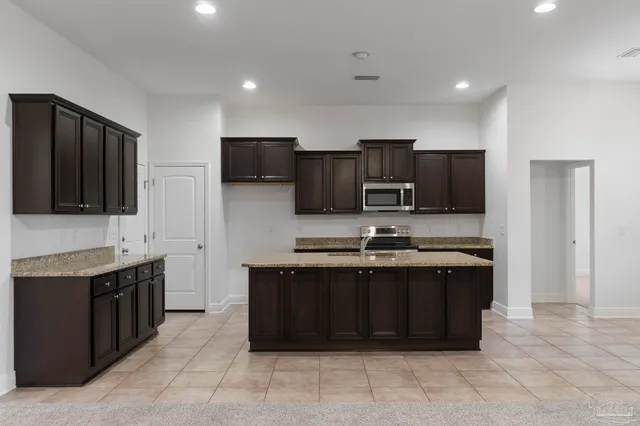 a large kitchen with stainless steel appliances granite countertop a sink and dishwasher a refrigerator with wooden cabinets