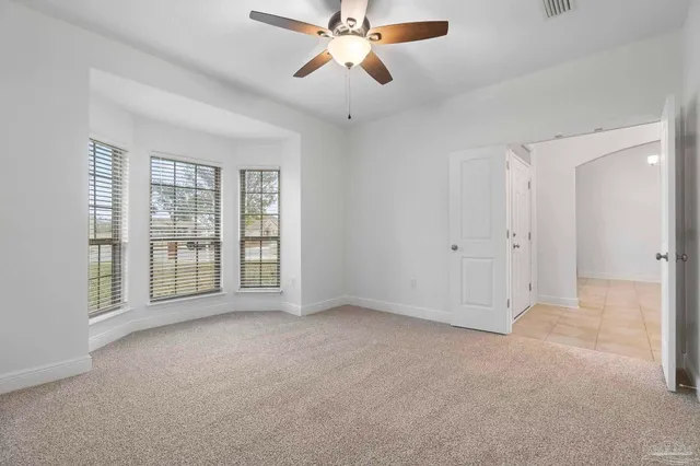 a view of an empty room with chandelier fan and a window