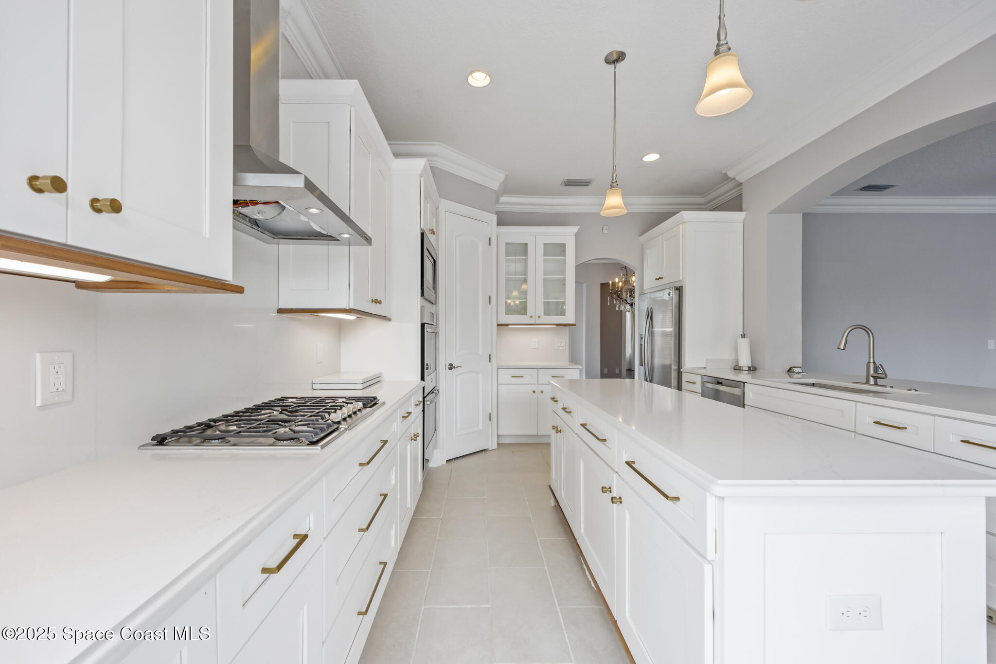 3326 Peninsula Circle Melbourne, FL 32940 - Photo 12 of 53 a large white kitchen with stainless steel appliances a stove a sink dishwasher and white cabinets with wooden floor