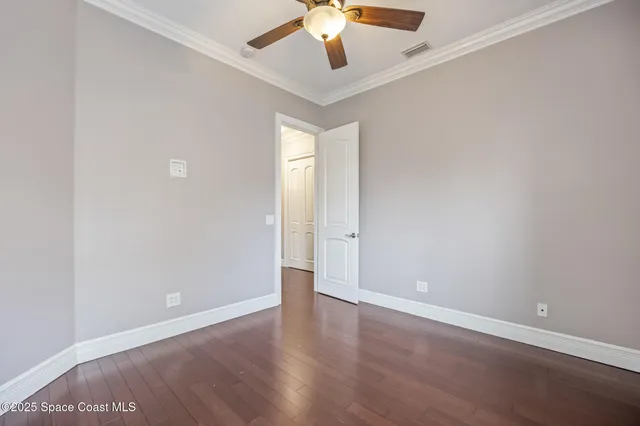 an empty room with wooden floor closet and windows