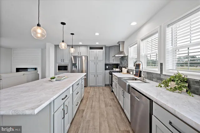 a large kitchen with kitchen island a large counter space a sink appliances and a large window