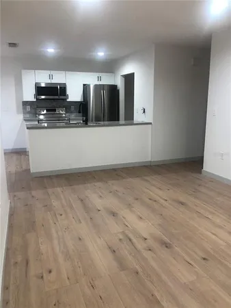 a large kitchen with stainless steel appliances wooden cabinets and a wooden floor