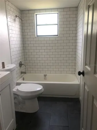a bathroom with a bathtub a toilet a sink and a window