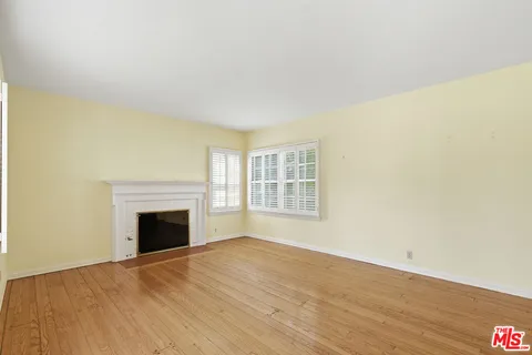 a view of empty room with a fireplace and wooden floor