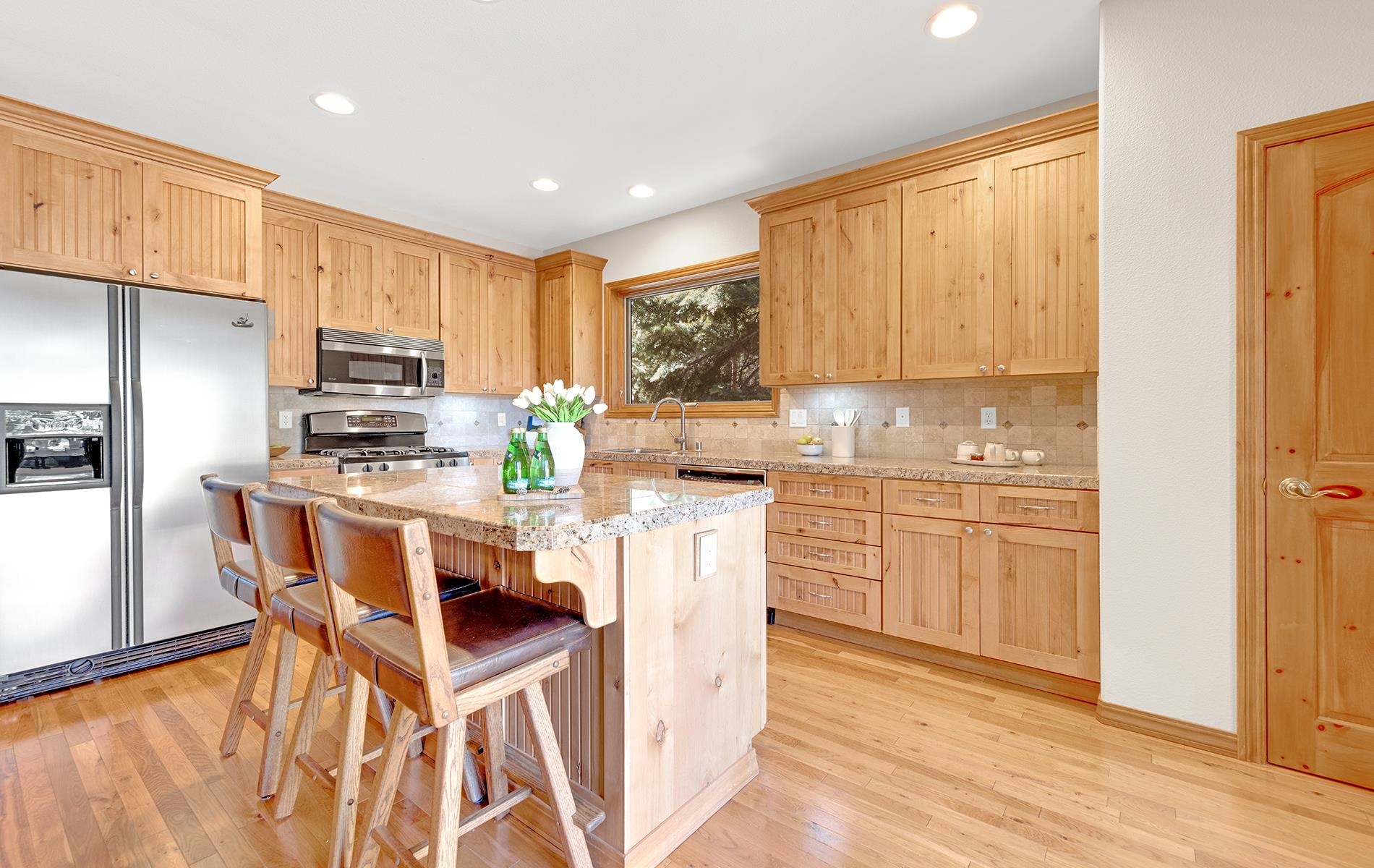 627 Deep Forest Road Lake Almanor, CA 96137 - Photo 8 of 29 a kitchen with kitchen island granite countertop wooden floors white cabinets and stainless steel appliances