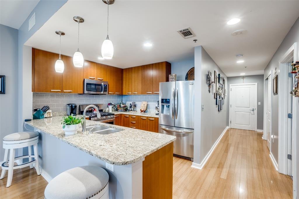 a kitchen with granite countertop kitchen island stainless steel appliances a refrigerator a sink a stove a microwave a center island and chairs