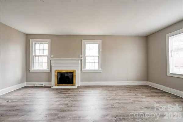 an empty room with windows and fireplace