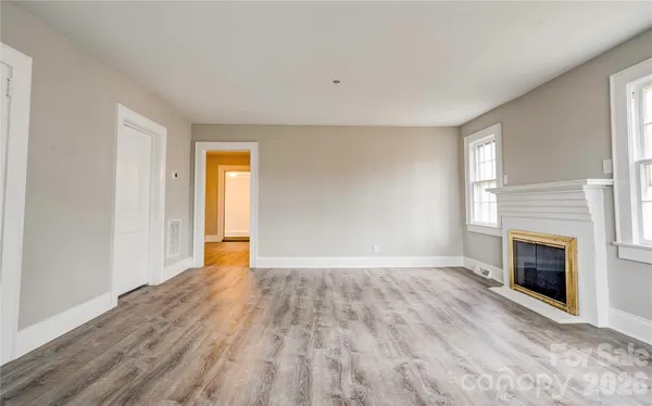 a view of empty room with wooden floor and fireplace