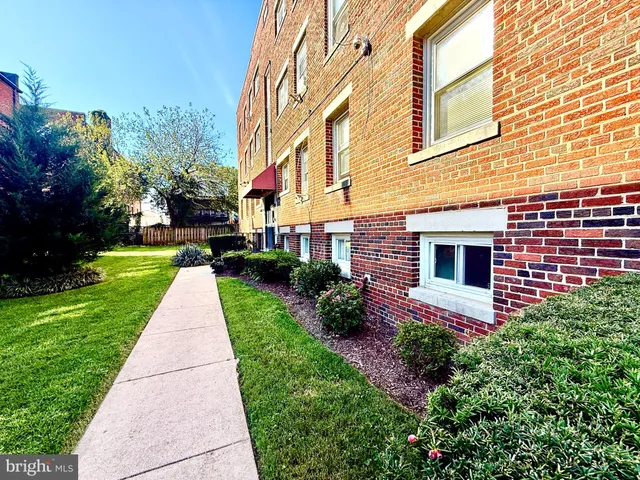a front view of a brick house with a yard and many windows