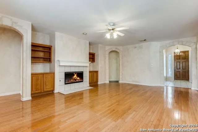 a view of an empty room with wooden floor fireplace and a window