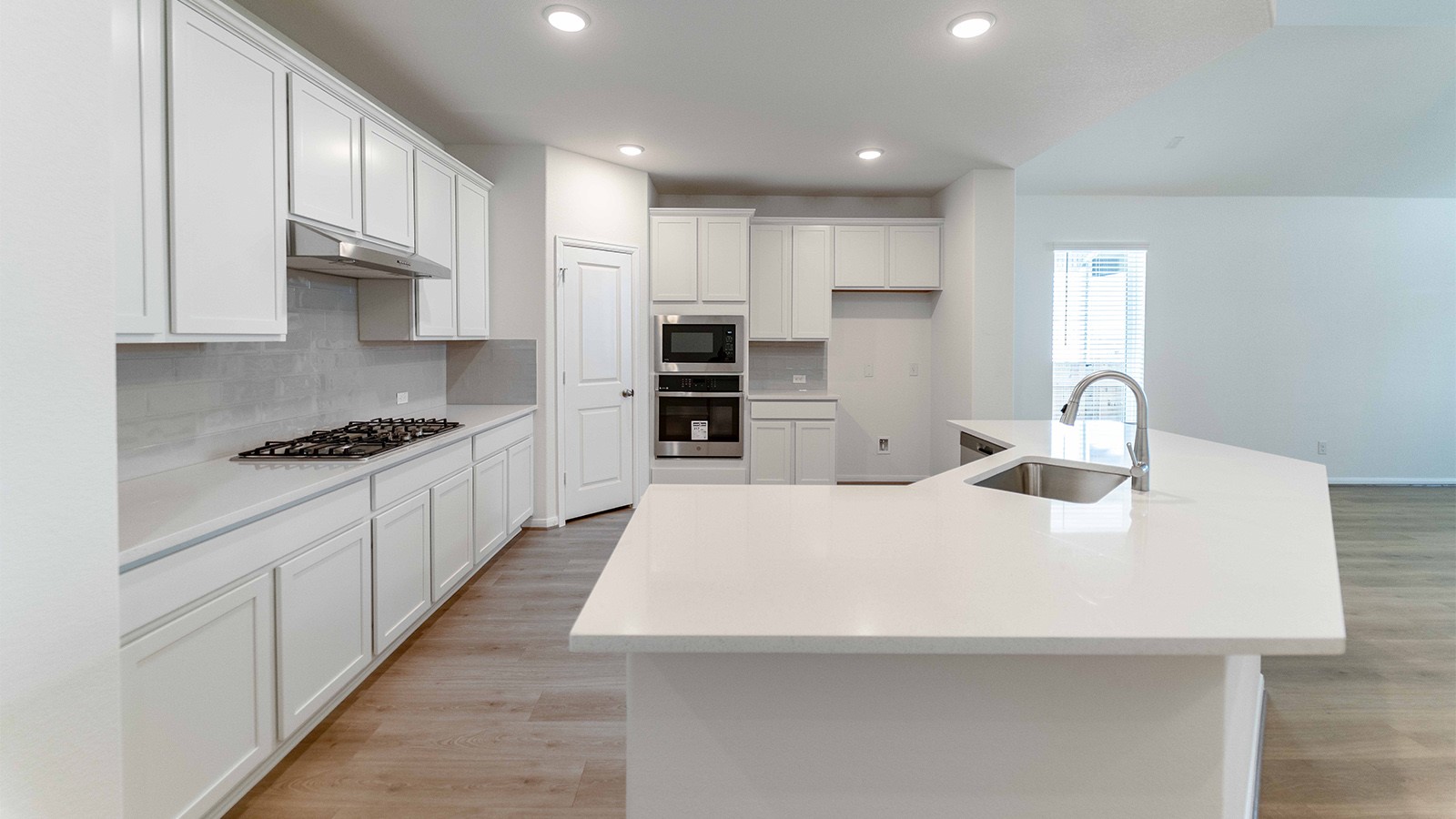 251 Grey Leaf Road Buda, TX 78610 - Photo 4 of 17 Kitchen featuring a kitchen island with sink, backsplash, stainless steel appliances, white cabinets, and light wood-style floors