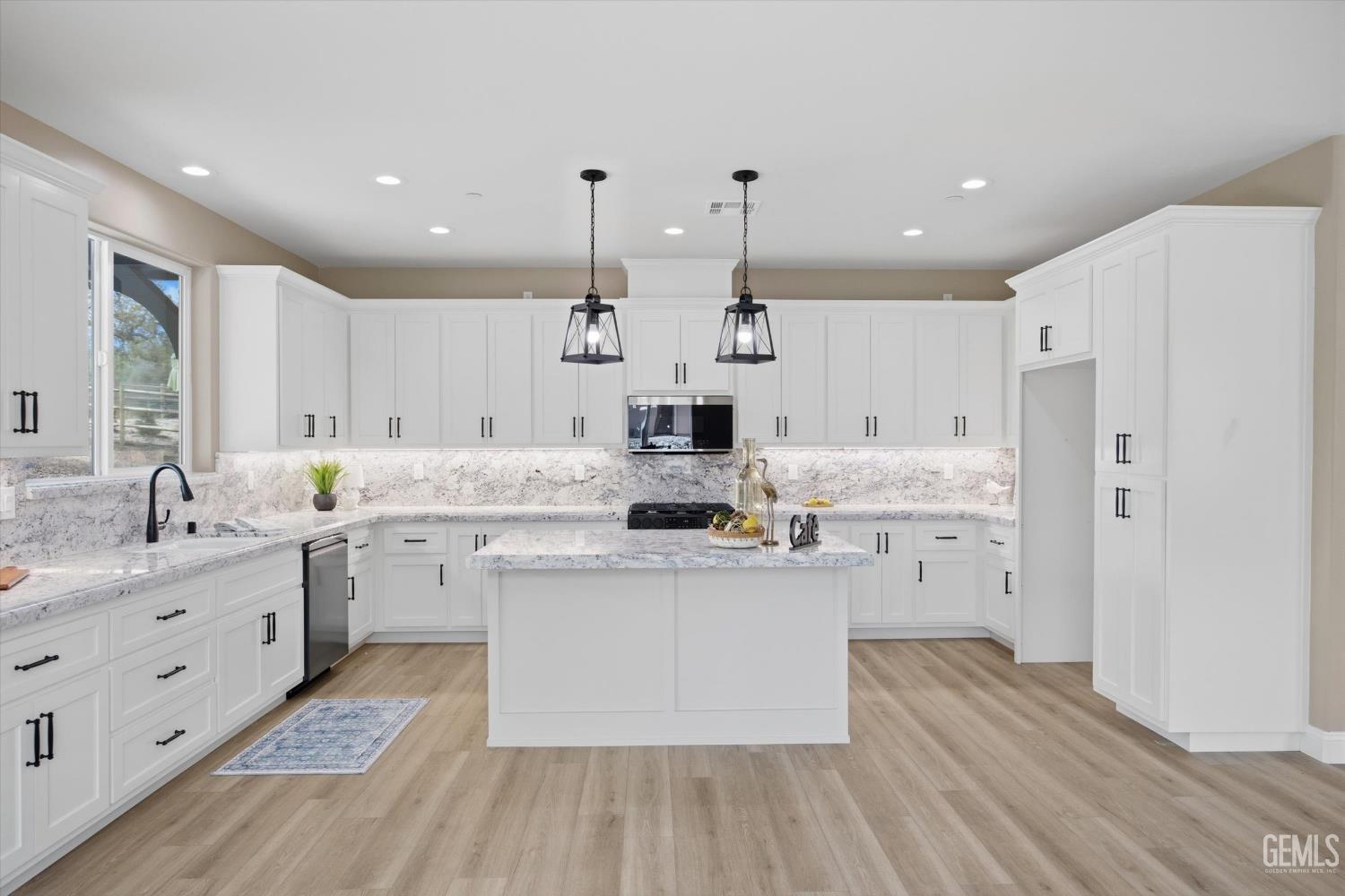 Undisclosed Address Tehachapi, CA 93561 - Photo 22 of 47 a large kitchen with stainless steel appliances kitchen island granite countertop a sink dishwasher a refrigerator and white cabinets with wooden floor