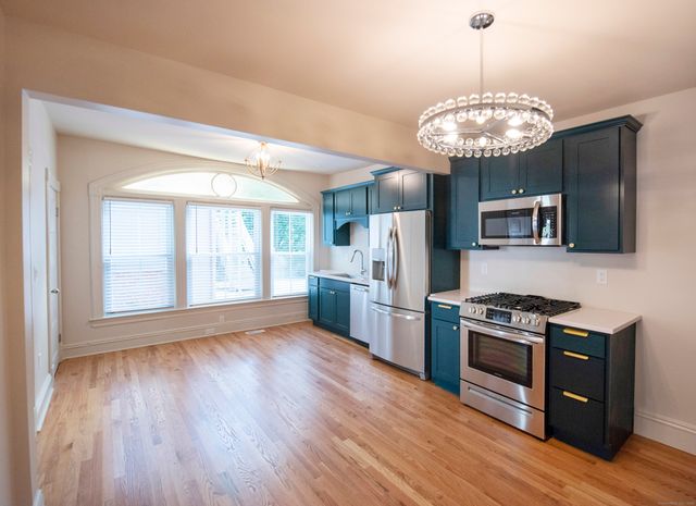 a kitchen with stainless steel appliances granite countertop a stove refrigerator and a wooden floor