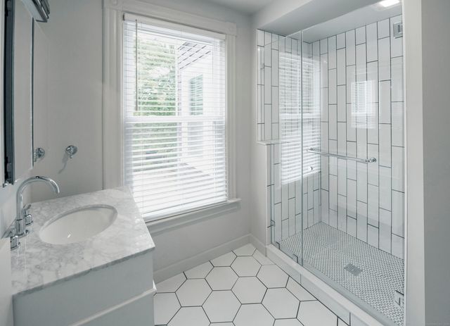 a bathroom with a granite countertop sink a shower and a window