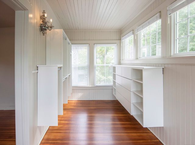 a view of a hallway with wooden floor and cabinet