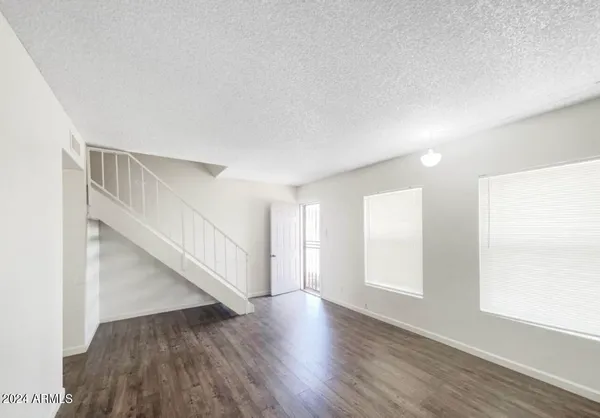 a view of an empty room with wooden floor and stairs