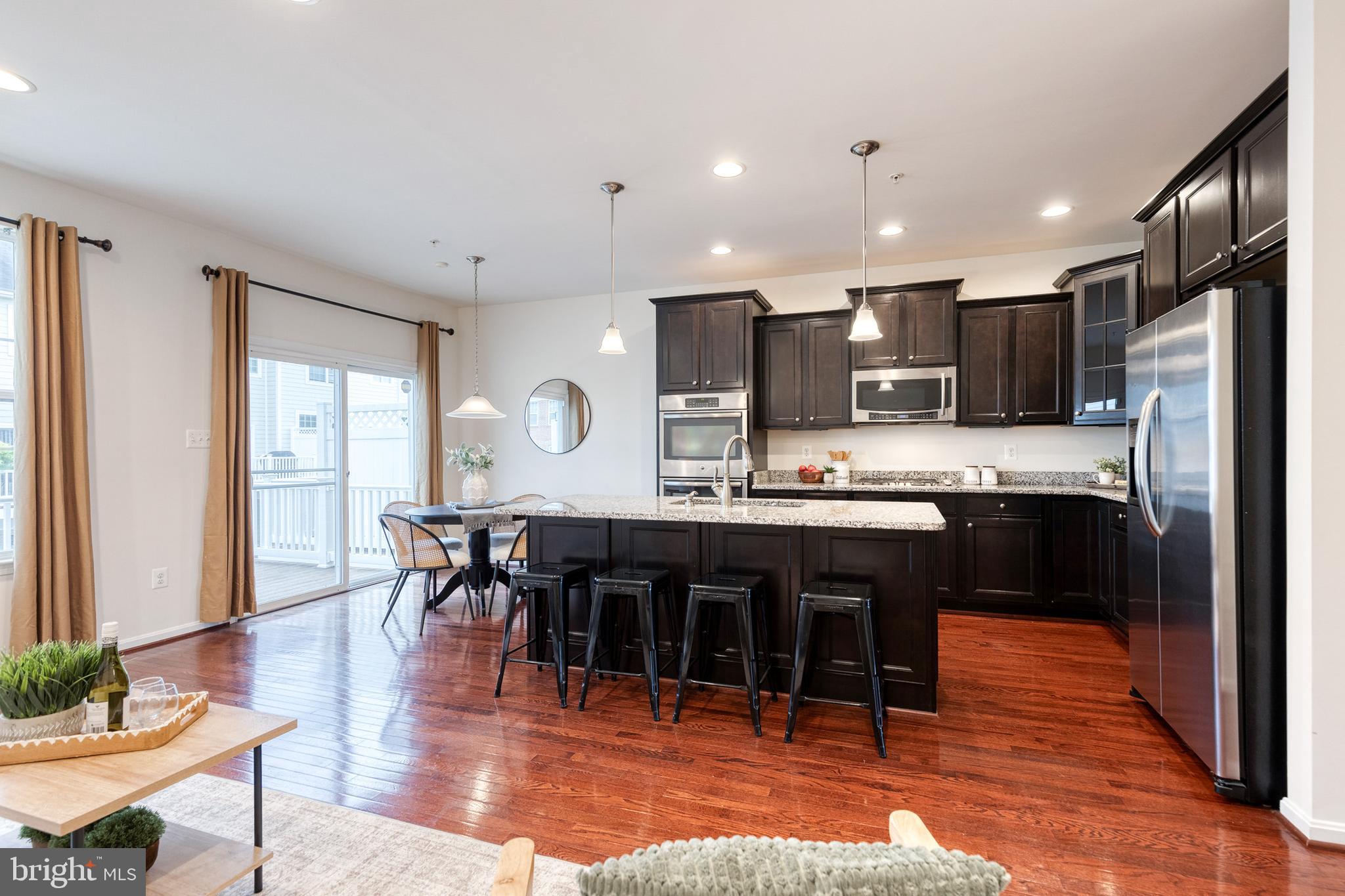 7951 Silver Oak Road Hanover, MD 21076 - Photo 17 of 41 a kitchen with stainless steel appliances granite countertop a refrigerator a stove a sink a dining table and chairs with wooden floor
