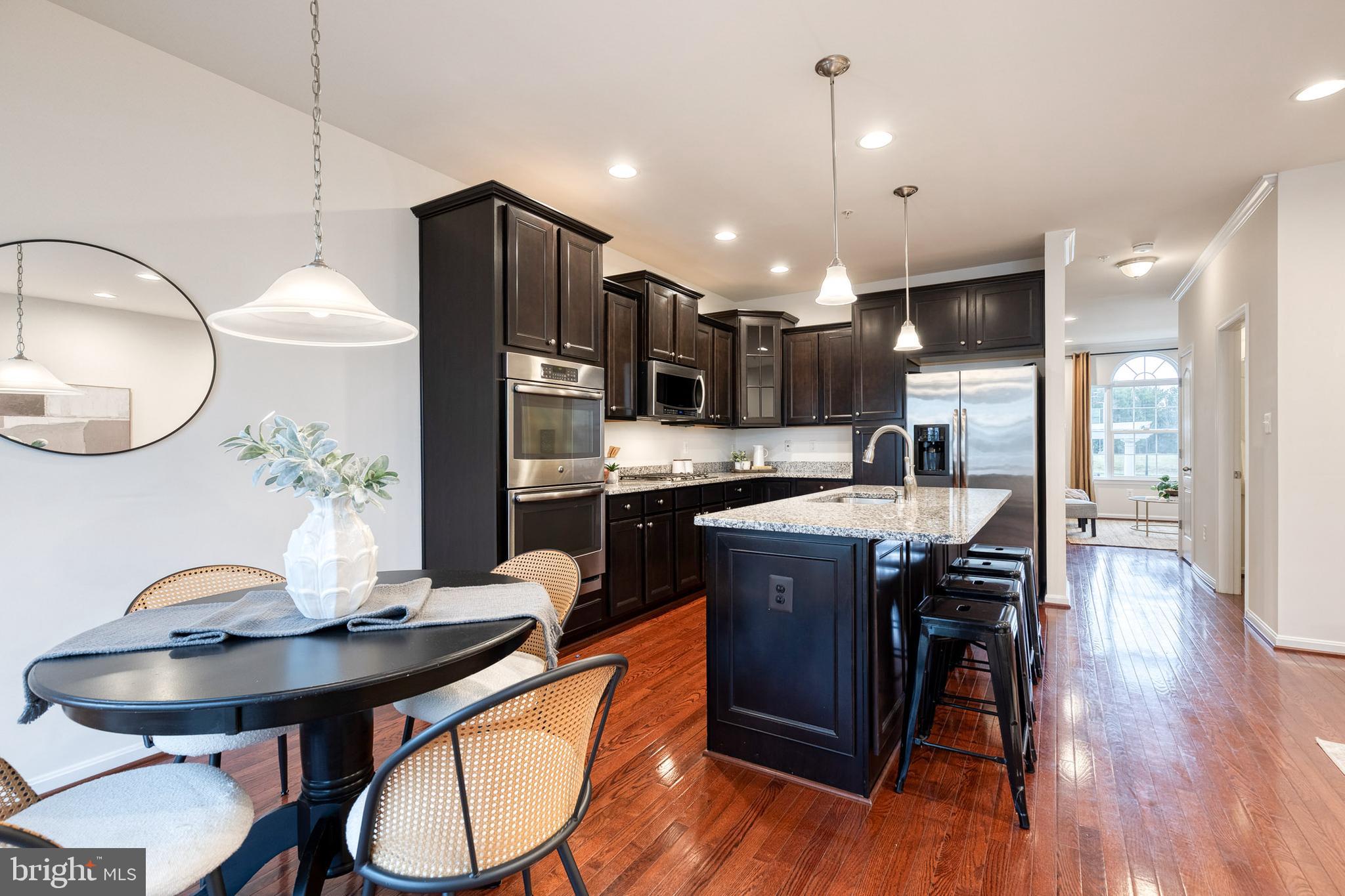7951 Silver Oak Road Hanover, MD 21076 - Photo 7 of 41 a kitchen with stainless steel appliances granite countertop a stove a refrigerator a kitchen island a dining table and chairs with wooden floor