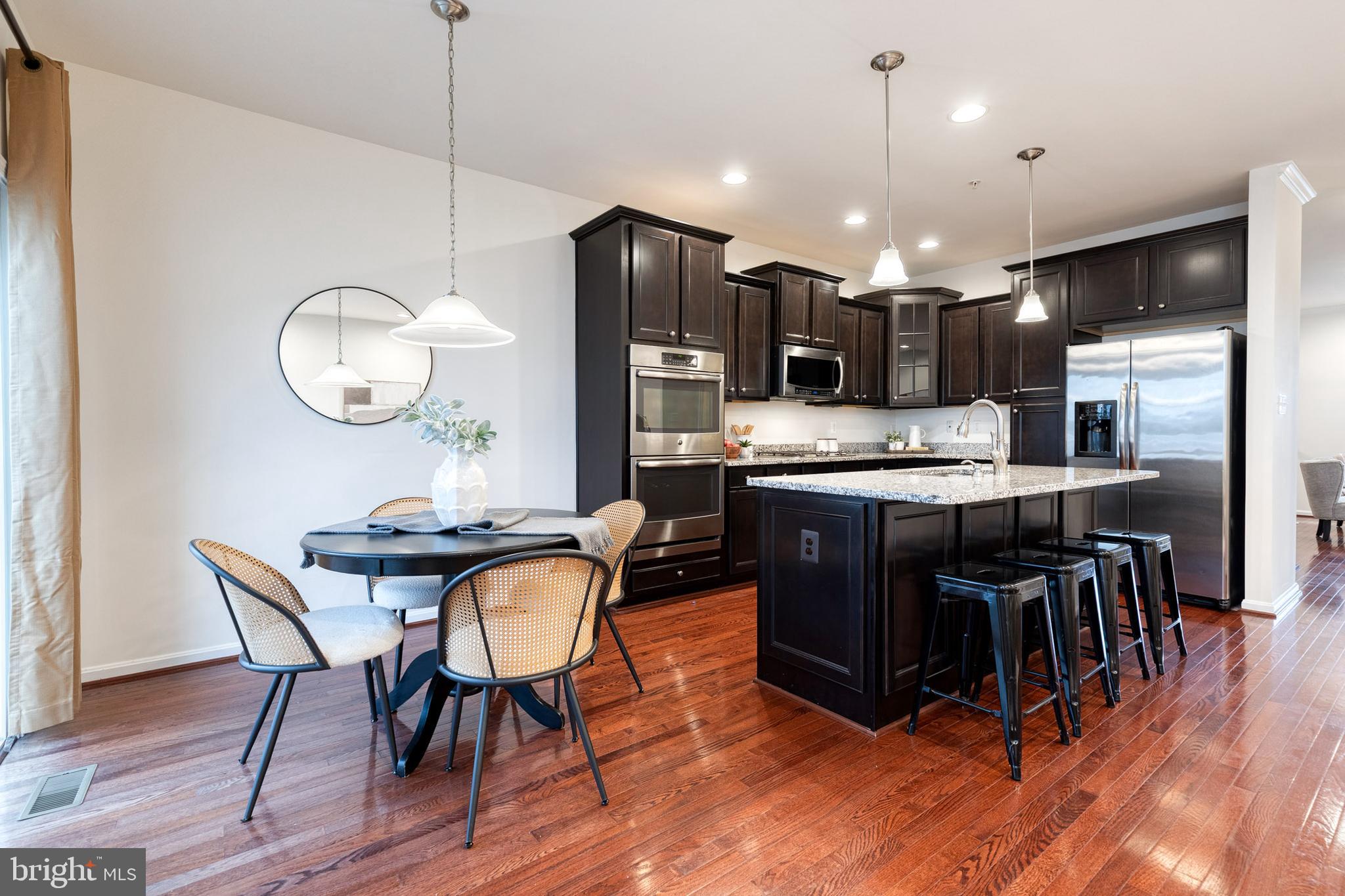 7951 Silver Oak Road Hanover, MD 21076 - Photo 8 of 41 a kitchen with stainless steel appliances kitchen island granite countertop a table chairs and a refrigerator