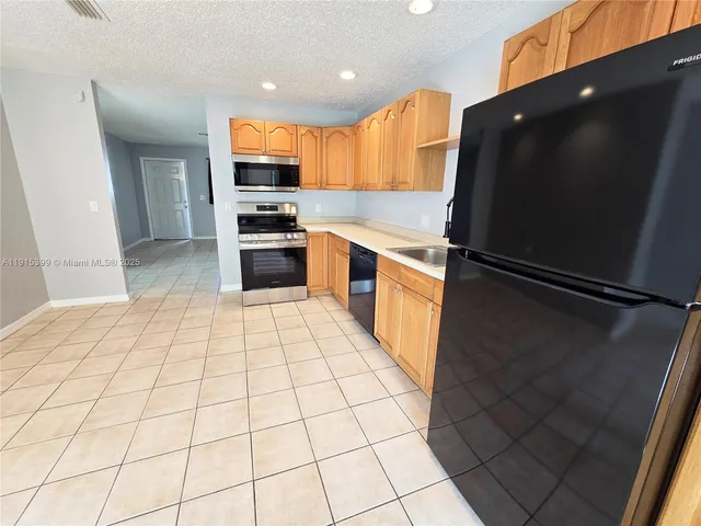 a kitchen with stainless steel appliances granite countertop a refrigerator and a stove top oven