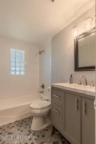 a bathroom with a granite countertop sink toilet and mirror